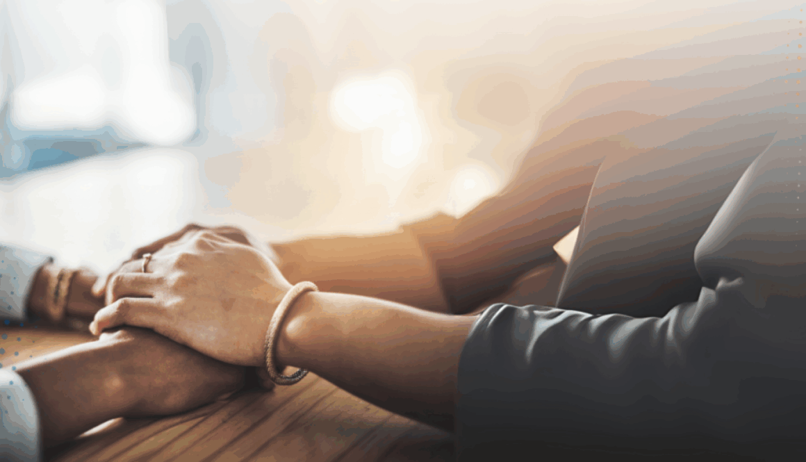 Two people holding hands in a comforting gesture, symbolising support and empathy.