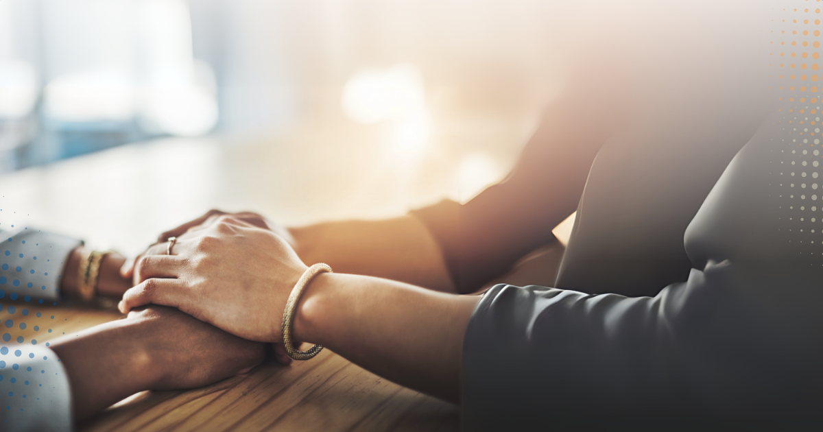 Two people holding hands in a comforting gesture, symbolising support and empathy.